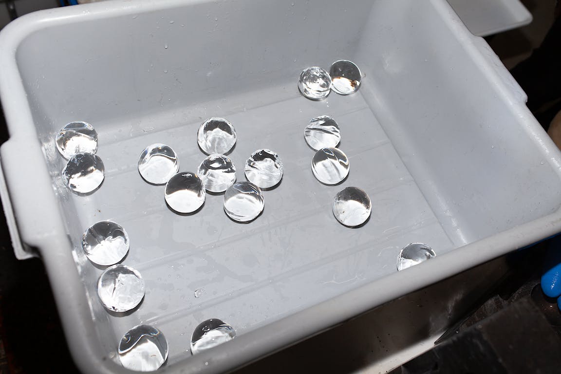 Many perfect spheres of ice sit within a plastic tub.